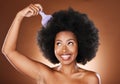 Beauty, hair care and black woman with afro comb in studio isolated on a brown background. Afro, wellness and happy