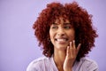 Beauty, hair and woman with hands on face in studio for natural, cosmetic or wellness on purple background. Haircare