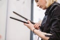 Beauty, hairstyle concept, happy young woman and hairdresser with hair iron making hairdo at hair salon. Woman Having Royalty Free Stock Photo