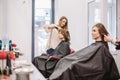 Beauty, hairstyle concept, happy young woman and hairdresser with hair iron making hairdo at hair salon. Woman Having Royalty Free Stock Photo