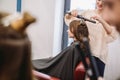 Beauty, hairstyle concept, happy young woman and hairdresser with hair iron making hairdo at hair salon. Woman Having Royalty Free Stock Photo