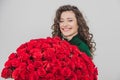 Closeup portrait of a satisfied young woman dressed in green dress holding huge bouquet of roses  over white Royalty Free Stock Photo