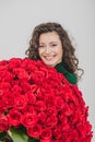 Closeup portrait of a satisfied young woman dressed in green dress holding huge bouquet of roses  over white Royalty Free Stock Photo