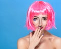 Beauty head shot. Cute Young woman with creative pop art make up and pink wig looking at the camera on blue background