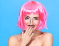 Beauty head shot. Cute Young woman with creative pop art make up and pink wig looking at the camera on blue background