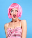 Beauty head shot. Surprised Young woman with creative pop art make up and pink wig looking at the camera on blue background Royalty Free Stock Photo