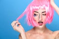 Beauty head shot. Young woman with creative pop art make up and pink wig looking at the side on blue background Royalty Free Stock Photo