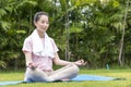 Beauty and healthy woman exercise and doing meditation of yoga on exercise mat in the outdoor park - fitness, sport, yoga Royalty Free Stock Photo