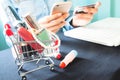 Beauty items in shopping trolley and woman using smartphone and Royalty Free Stock Photo