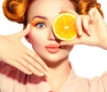 Beauty joyful teenage girl takes juicy oranges. Teen model girl with freckles, funny red hairstyle, yellow makeup and nails Royalty Free Stock Photo