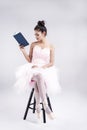 The beauty lady is wearing pink ballet dress and satin ballet shoes,sitting on black chair,reading book Royalty Free Stock Photo