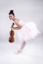 The beauty lady is wearing pink ballet dress, stand and bend body down,hold violin in hand,with smile and happy face, Royalty Free Stock Photo