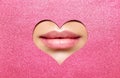 Beauty Lips Makeup Close up. Natural Plump Bright Lip Glossy Lipstick look through Heart Shaped Hole in Pink Glitter Paper. Lips