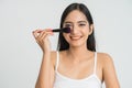 Beautiful young woman applying foundation powder or blush with makeup brush. Mixed race Asian Caucasian model. Royalty Free Stock Photo