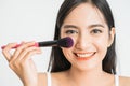 Beautiful young woman applying foundation powder or blush with makeup brush. Mixed race Asian Caucasian model. Royalty Free Stock Photo