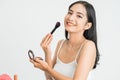 Beautiful young woman applying foundation powder or blush with makeup brush. Mixed race Asian Caucasian model. Royalty Free Stock Photo