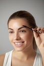 Beauty makeup. Beautiful  Woman shaping eyebrow closeup. Girl model with professional makeup using eyebrows brush Royalty Free Stock Photo