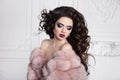 Beauty makeup. Brunette with long curly hairstyle, elegant fashion glamour woman in pink fur coat. Beautiful lady posing in white Royalty Free Stock Photo