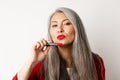 Beauty and makeup concept. Beautiful asian elderly woman pucker lips, showing red lipstick and looking sassy at camera Royalty Free Stock Photo
