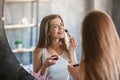 Beauty and makeup. Pretty young woman applying blusher on her face near mirror at home Royalty Free Stock Photo