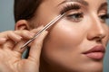 Beauty Makeup. Woman Applying Black False Eyelashes With Tweezer