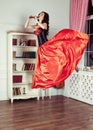 Beauty in mid-air. Full length studio shot of attractive young woman in orange dress hovering in air and playing the Royalty Free Stock Photo