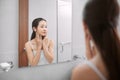 Beauty in mirror reflection. Over the shoulder view of beautiful woman touching her face while looking in the mirror Royalty Free Stock Photo