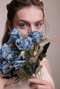 Beauty model covering face with blue flowers bunch portrait Royalty Free Stock Photo