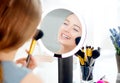 Beauty model girl applying makeup. Beautiful young woman looking in the mirror and applying cosmetic with a big brush Royalty Free Stock Photo