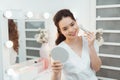 Beauty model girl applying makeup and smiling. Beautiful young woman looking in the mirror and applying cosmetic with a big brush Royalty Free Stock Photo