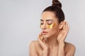 Beauty model girl face with healthy fresh skin. Woman with under eye collagen gold pads. Royalty Free Stock Photo