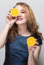 Beauty Model Girl takes Juicy Oranges. Beautiful Joyful teen girl funny red hairstyle and makeup. Professional make up. Royalty Free Stock Photo