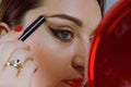 Beauty model teenage girl looking in the mirror and applying mascara make up. Beautiful young woman apply makeup Royalty Free Stock Photo