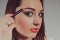 Beauty model teenage girl looking in the mirror and applying mascara make up. Beautiful young woman apply makeup Royalty Free Stock Photo