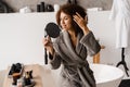Beauty morning routine of african girl in bathroom. Attractive african american woman in bathrobe is looking in the