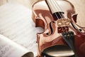 Beauty of musical instruments. Close up view of brown violin lying on sheets with music notes on wooden floor. Violin Royalty Free Stock Photo