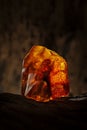 Beauty of natural raw amber. A piece of yellow and red semi transparent natural amber on piece of stoned wood. Royalty Free Stock Photo