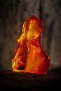 Beauty of natural raw amber. A piece of yellow-red transparent natural amber on piece of stoned wood Royalty Free Stock Photo