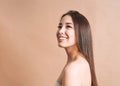 Beauty nude portrait of happy young beautiful asian woman with healthy dark long hair in top bando on beige background isolated Royalty Free Stock Photo