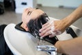 Beauty and people concept - happy young woman with hairdresser washing head at hair salon