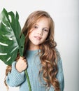 Beauty and fashion concept: Little curly girl child wearing blue sweater and holding flower Royalty Free Stock Photo