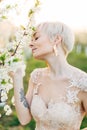 Beauty, people, summer, spring and wedding concept - side view portrait of beautiful young woman touching tree blossom Royalty Free Stock Photo