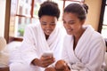 Beauty, phone and spa with woman friends in robes for luxury pampering or treatment together. Smile, app and social