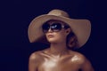 Beauty photo of attractive sensual woman wearing straw brimmed hat and big sunglasses posing on dark studio background Royalty Free Stock Photo