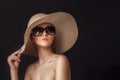 Beauty photo of attractive sensual woman wearing straw brimmed hat and big sunglasses posing on dark studio background Royalty Free Stock Photo