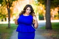 Beauty plus size model in blue dress outdoors, fat woman in autumn park among yellow leaves Royalty Free Stock Photo