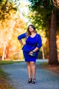 Beauty plus size model in blue dress outdoors, fat woman in autumn park among yellow leaves Royalty Free Stock Photo