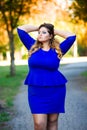 Beauty plus size model in blue dress outdoors, fat woman in autumn park among yellow leaves Royalty Free Stock Photo