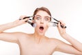 Beauty portrait of amazed funny young woman with makeup brushes Royalty Free Stock Photo