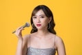 Beauty of portrait asian woman applying make up with brush of cheek on yellow background
